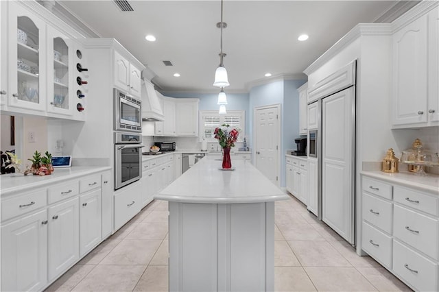 kitchen with white cabinets, light tile patterned floors, built in appliances, and a kitchen island