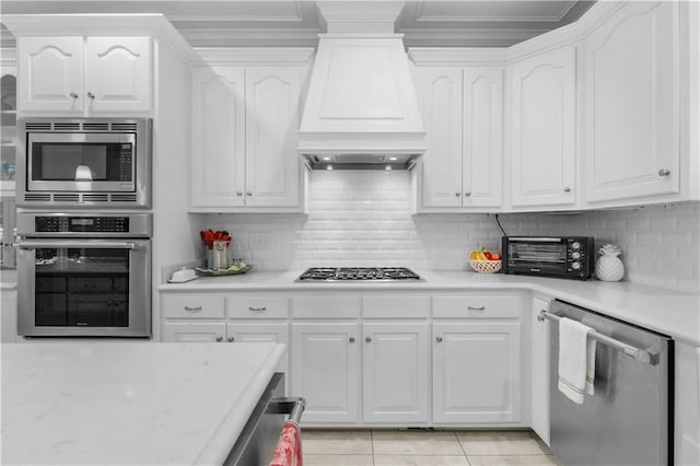 kitchen featuring white cabinetry, appliances with stainless steel finishes, light tile patterned flooring, a toaster, and custom exhaust hood