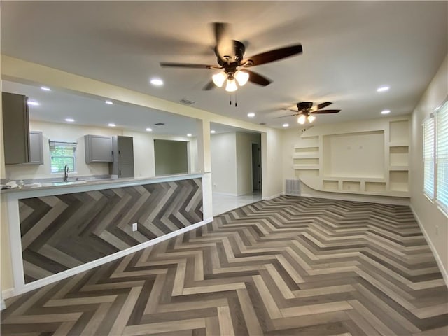 interior space with sink, parquet floors, gray cabinets, and ceiling fan