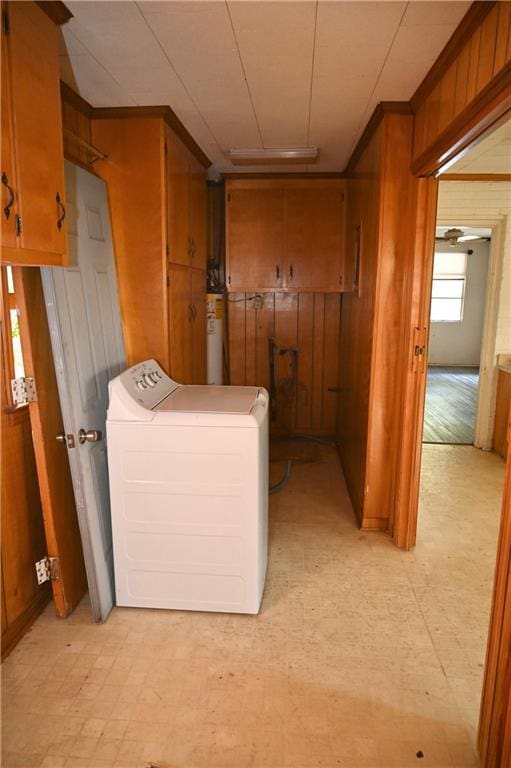 laundry room featuring cabinets, wooden walls, water heater, and washer / dryer