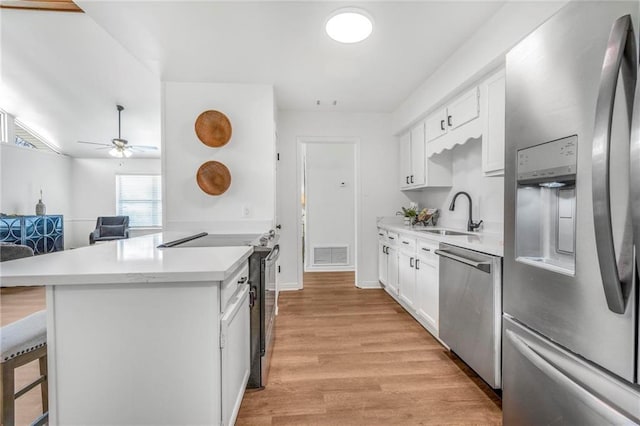 kitchen with visible vents, a breakfast bar, light countertops, stainless steel appliances, and a sink