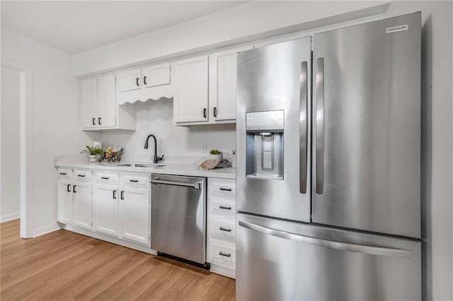 kitchen with light countertops, light wood-style flooring, appliances with stainless steel finishes, white cabinets, and a sink