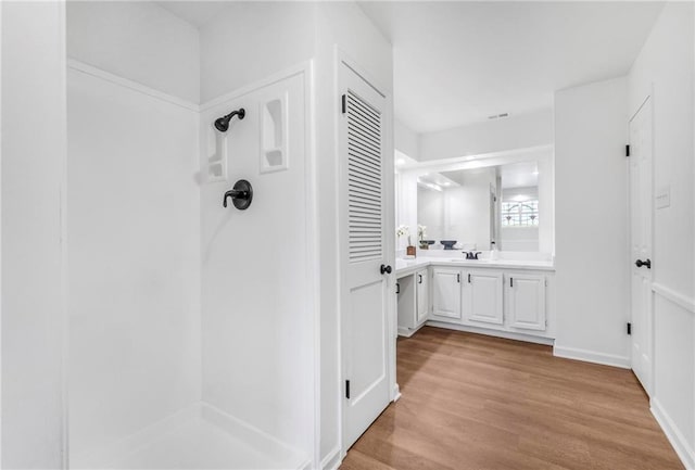 full bath featuring baseboards, vanity, walk in shower, and wood finished floors