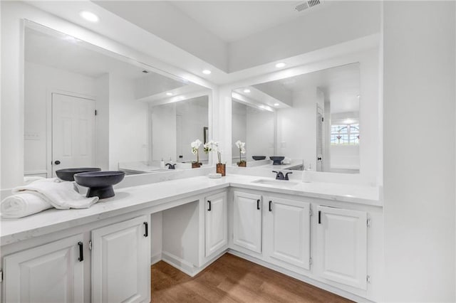 bathroom featuring visible vents, a sink, wood finished floors, recessed lighting, and double vanity