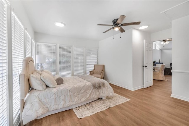 bedroom featuring ceiling fan, attic access, baseboards, and wood finished floors