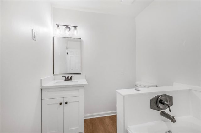 bathroom with vanity, a bathing tub, wood finished floors, and baseboards