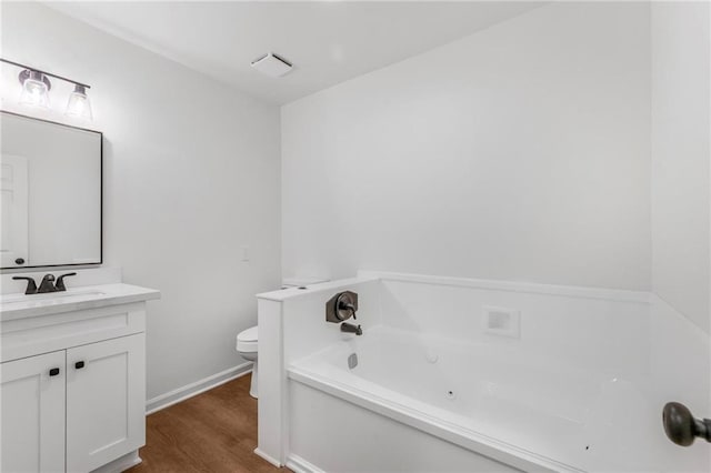 full bath with baseboards, toilet, wood finished floors, a tub with jets, and vanity