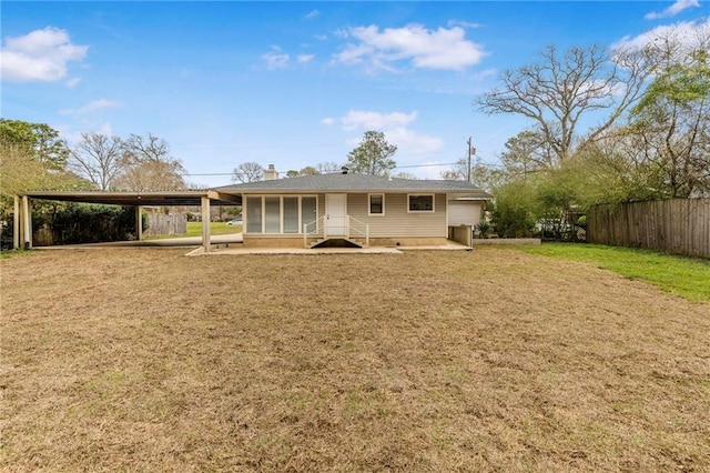 view of front of property featuring entry steps, fence, a front yard, a carport, and a chimney