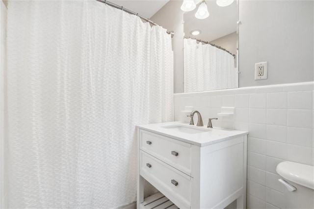 bathroom featuring vanity, toilet, and tile walls