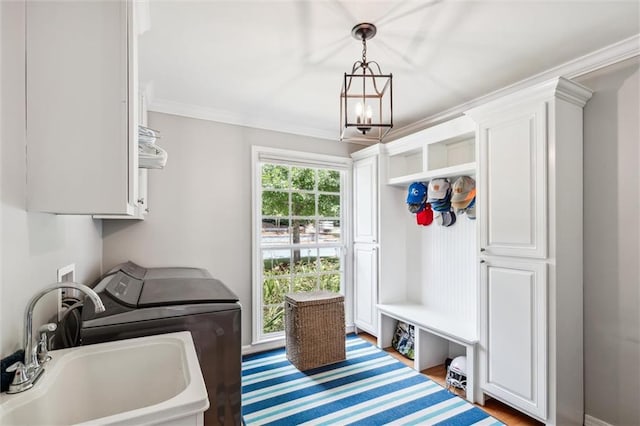 laundry room featuring sink, a chandelier, cabinets, ornamental molding, and washing machine and clothes dryer