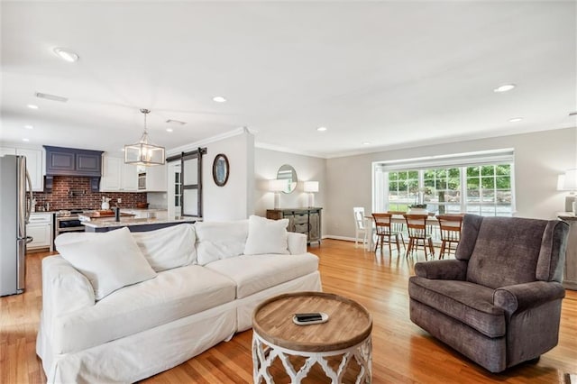 living room featuring ornamental molding, a barn door, and light wood-type flooring