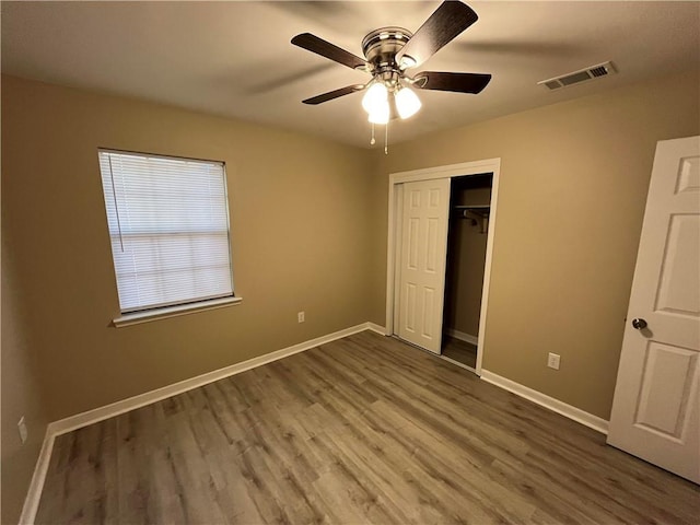 unfurnished bedroom with hardwood / wood-style floors, ceiling fan, and a closet