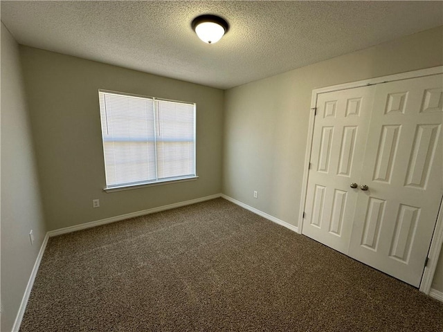 unfurnished room with dark colored carpet and a textured ceiling