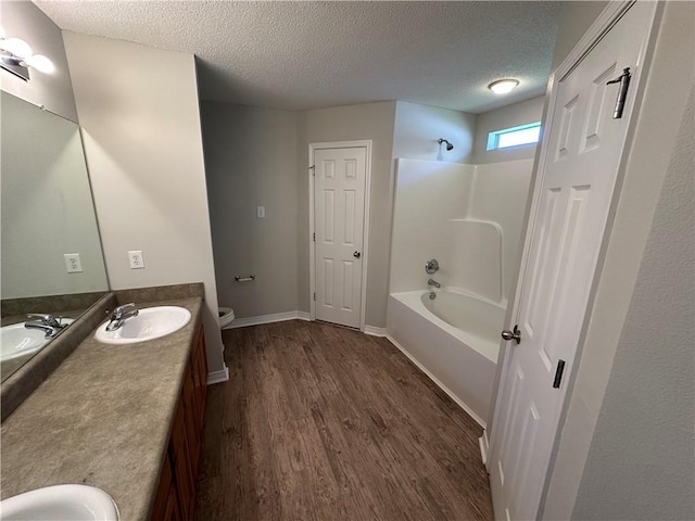 full bathroom featuring hardwood / wood-style floors, vanity, and a textured ceiling