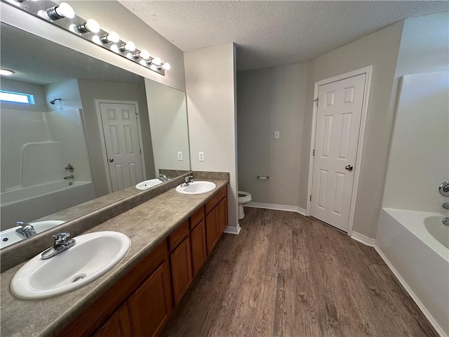 full bathroom with hardwood / wood-style floors, a textured ceiling, toilet, shower / tub combination, and vanity