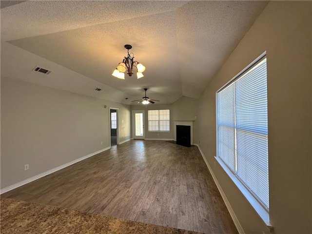 unfurnished living room featuring a textured ceiling, lofted ceiling, ceiling fan with notable chandelier, and dark hardwood / wood-style floors