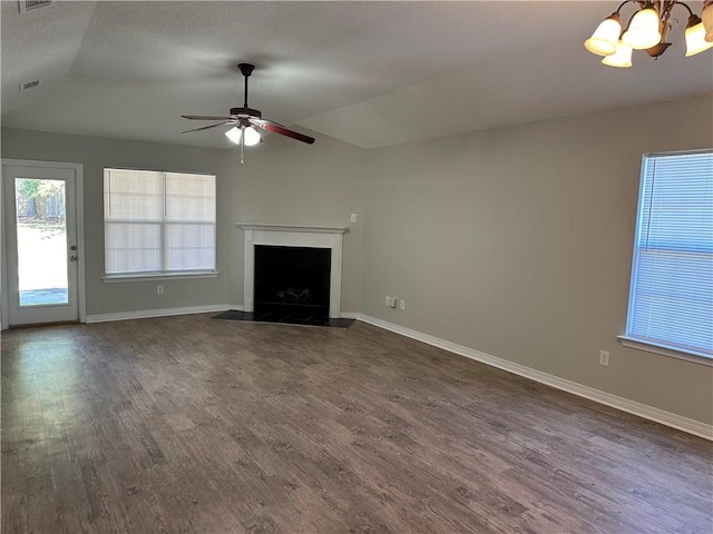 unfurnished living room with ceiling fan with notable chandelier, dark hardwood / wood-style flooring, lofted ceiling, and a textured ceiling