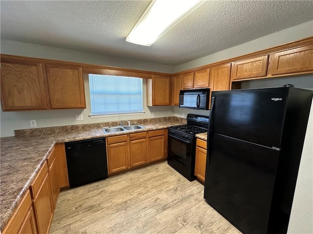 kitchen featuring sink, black appliances, a textured ceiling, and light hardwood / wood-style floors