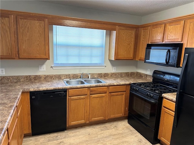 kitchen with black appliances, a textured ceiling, sink, and light hardwood / wood-style flooring