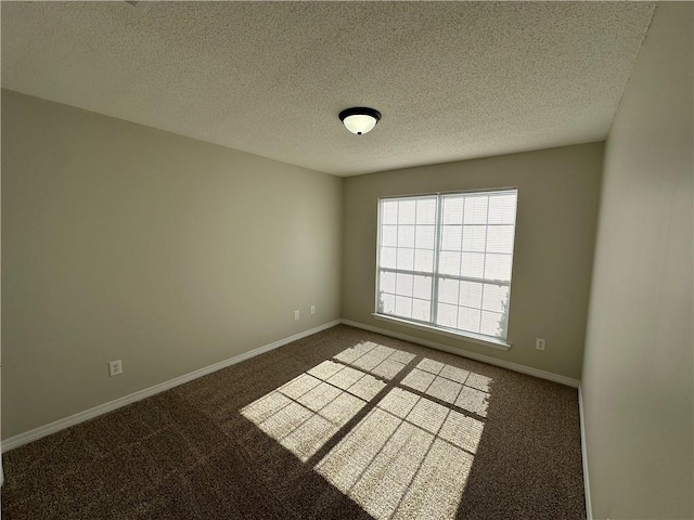 spare room featuring a textured ceiling and dark carpet