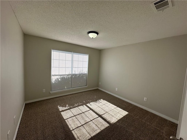 spare room with dark colored carpet and a textured ceiling