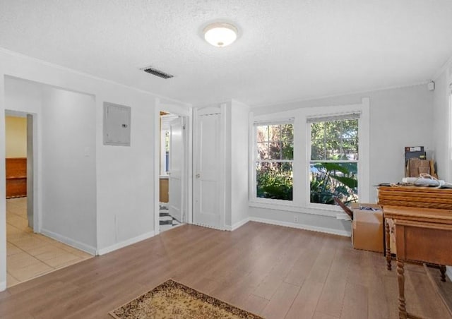 interior space featuring electric panel, a textured ceiling, and light wood-type flooring