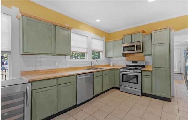 kitchen with sink, green cabinetry, appliances with stainless steel finishes, tasteful backsplash, and butcher block counters