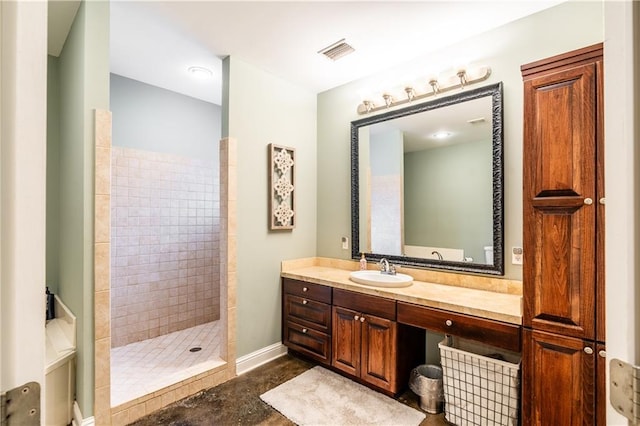 bathroom with a tile shower and vanity