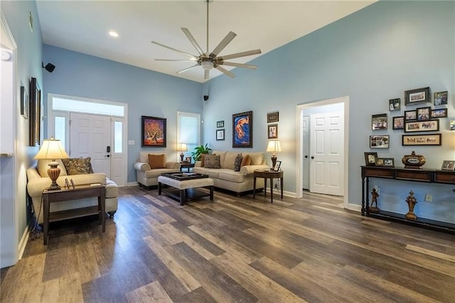 living room with a high ceiling, dark wood-type flooring, and ceiling fan