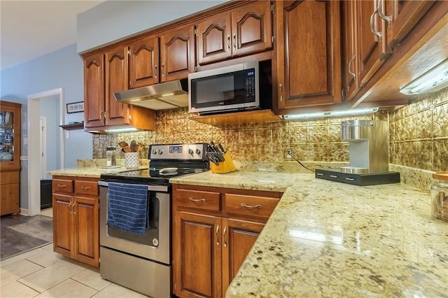 kitchen featuring appliances with stainless steel finishes, decorative backsplash, light tile patterned flooring, and light stone counters