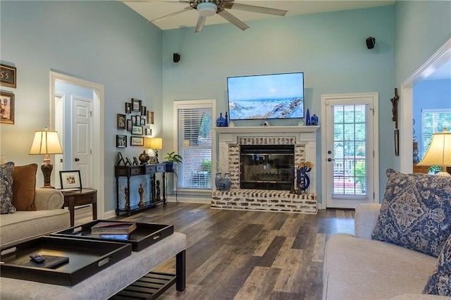 living room with a brick fireplace, ceiling fan, high vaulted ceiling, and dark hardwood / wood-style flooring