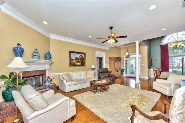 living room featuring ceiling fan, wood-type flooring, crown molding, and decorative columns