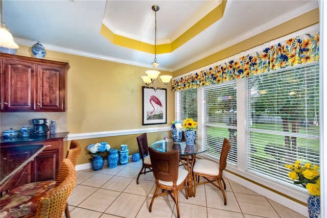 tiled dining area featuring a notable chandelier, ornamental molding, and a tray ceiling