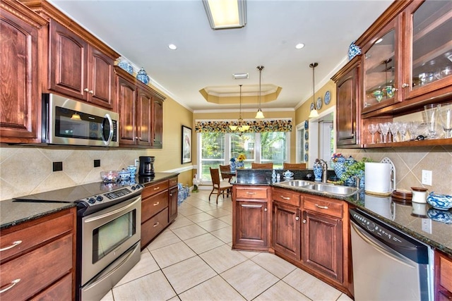 kitchen featuring sink, hanging light fixtures, appliances with stainless steel finishes, a tray ceiling, and a chandelier