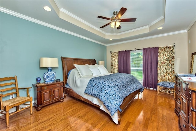 bedroom featuring a raised ceiling, ceiling fan, crown molding, and hardwood / wood-style floors