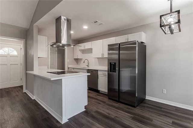 kitchen with dark wood-type flooring, white cabinetry, island range hood, appliances with stainless steel finishes, and kitchen peninsula