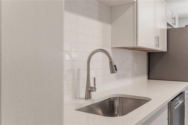 kitchen featuring dishwasher, sink, decorative backsplash, and white cabinets