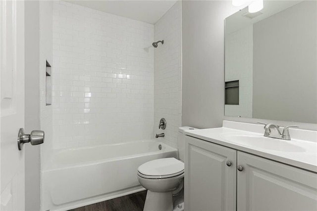 full bathroom with tiled shower / bath combo, wood-type flooring, vanity, and toilet