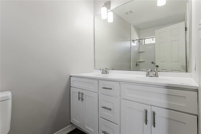 bathroom with vanity, toilet, and a shower