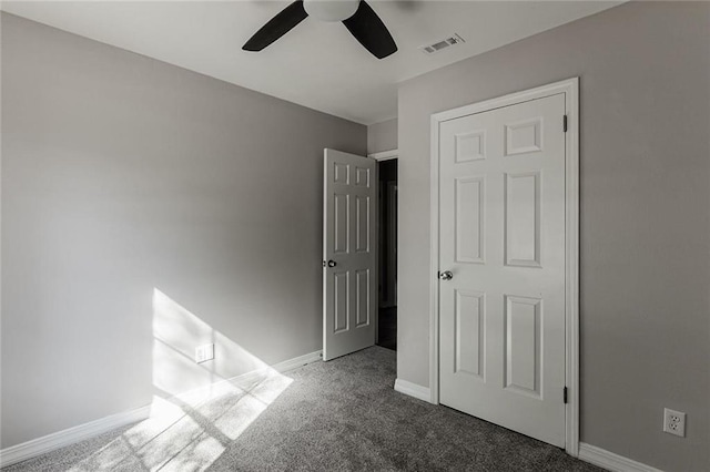 unfurnished bedroom with dark carpet and ceiling fan