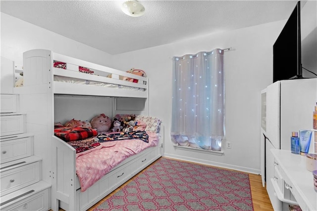 bedroom with a textured ceiling and light hardwood / wood-style floors