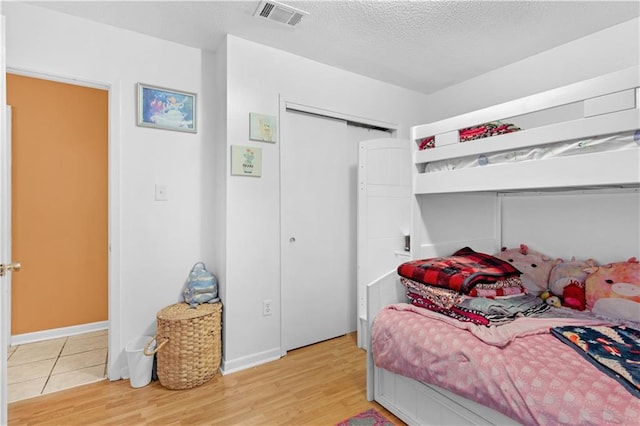 bedroom featuring wood-type flooring, a textured ceiling, and a closet