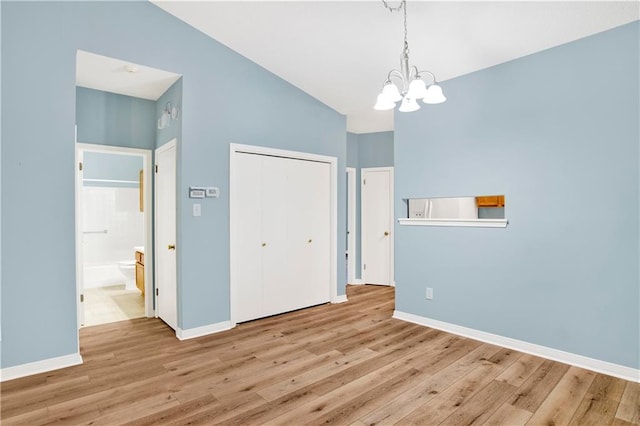 unfurnished dining area featuring an inviting chandelier, baseboards, and wood finished floors