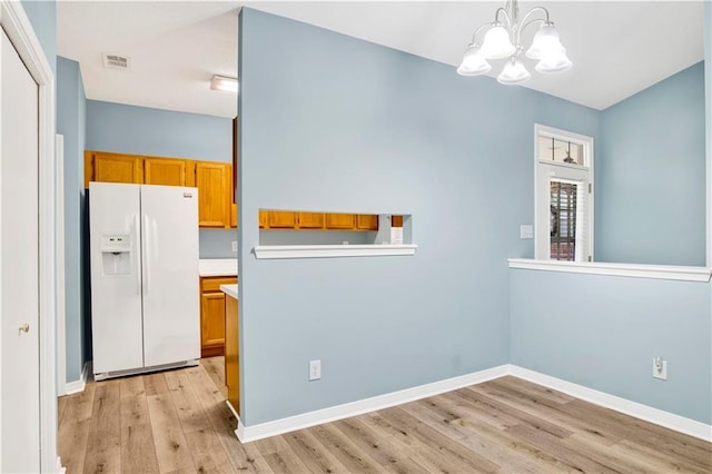 unfurnished dining area featuring an inviting chandelier, baseboards, visible vents, and light wood-type flooring