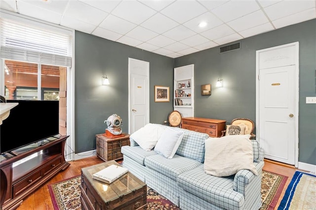 living room with light hardwood / wood-style floors and a drop ceiling