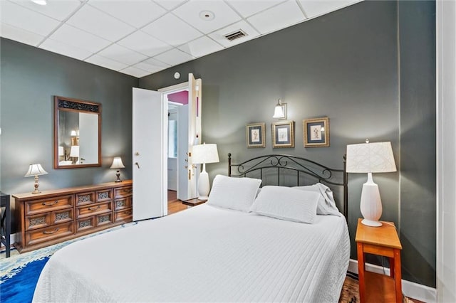 bedroom with a paneled ceiling and hardwood / wood-style flooring