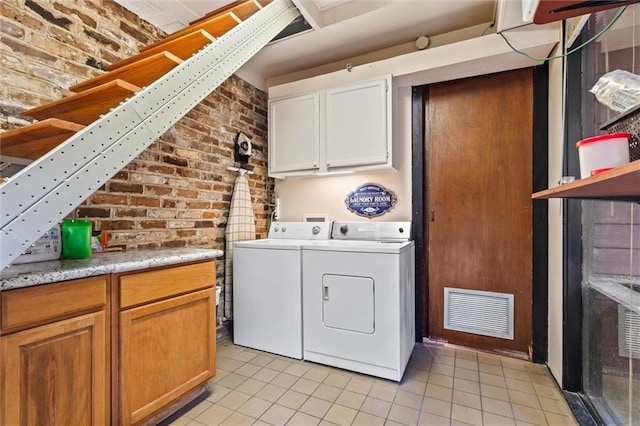 51 Jackson St N Unit A, Mobile, AL 36602 - laundry area featuring cabinet space, washing machine and clothes dryer, light tile patterned floors, and brick wall