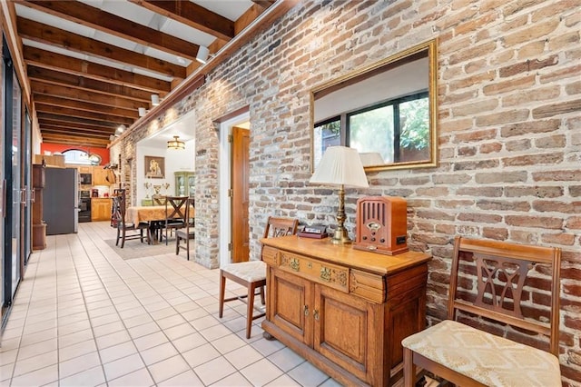 hallway with beam ceiling, light tile patterned flooring, and brick wall