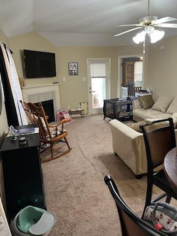 carpeted living room featuring lofted ceiling, a tile fireplace, and ceiling fan