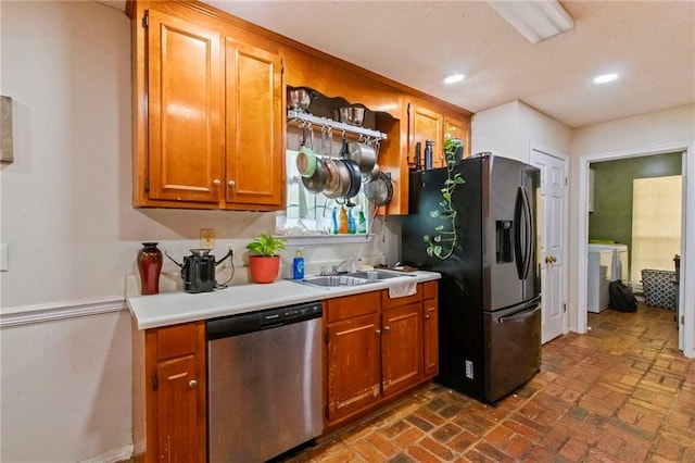 kitchen with appliances with stainless steel finishes, independent washer and dryer, and sink